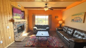 A cozy living room with a fireplace, leather sofas, a coffee table, and a TV mounted on the wall. - Two Bedroom Condo @ Spring Brook Resort (Wisconsin Dells)