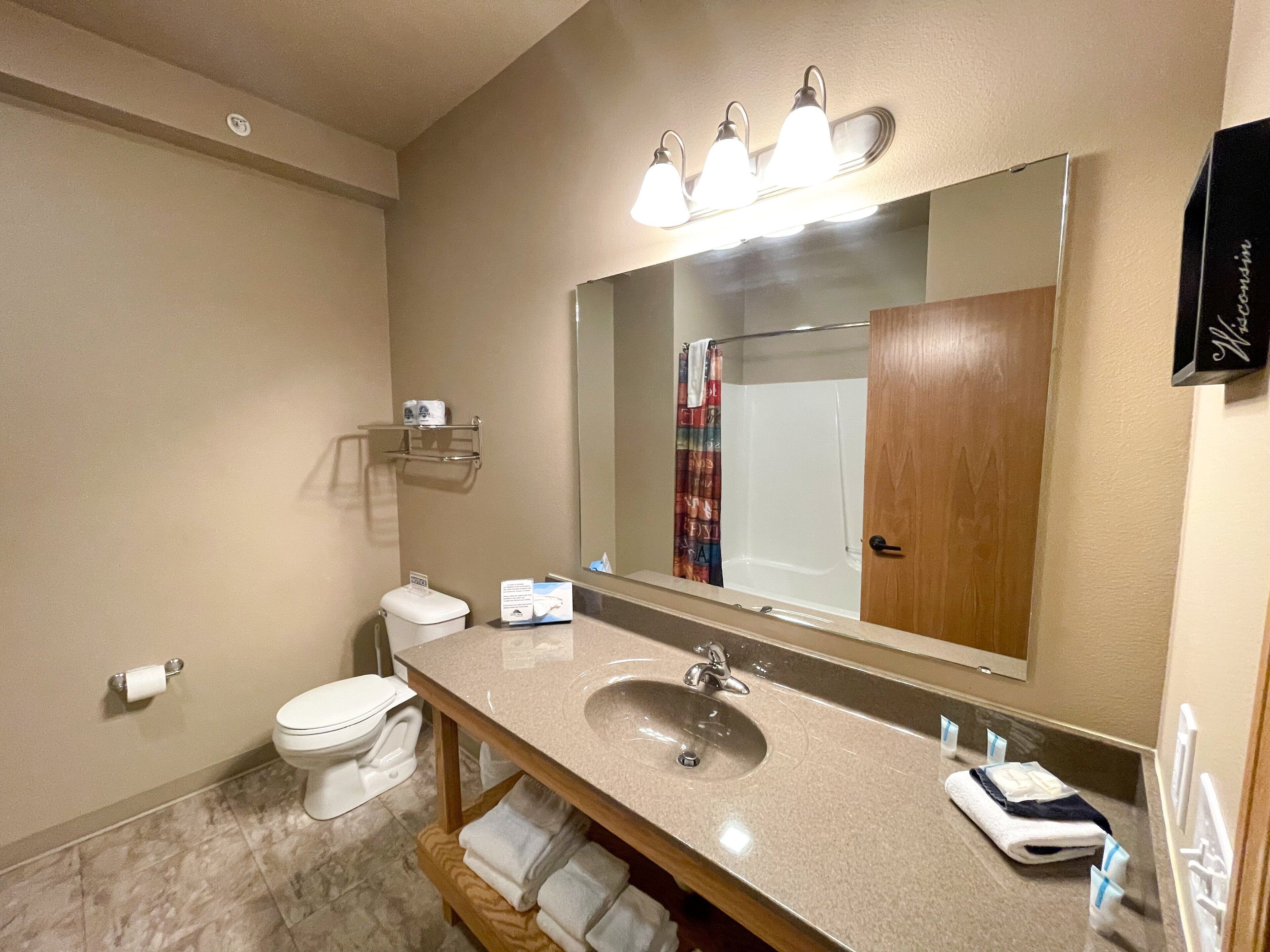 A bathroom with a sink, mirror, toilet, and towel rack.