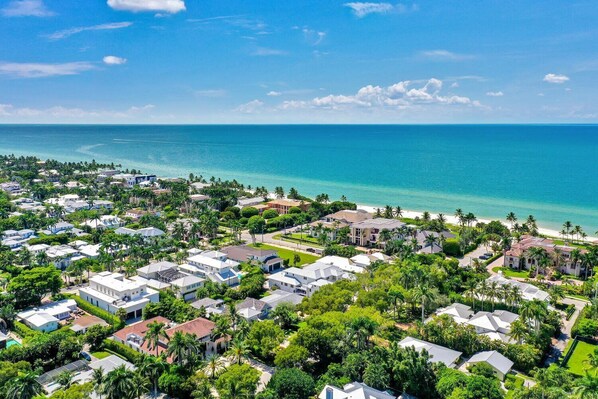 A coastal residential area with houses, palm trees, and a beach.