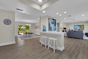 A spacious living area with a kitchen island, dining area, and a seating area with a sofa and chairs.