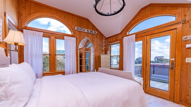 Ein Schlafzimmer mit einem großen Bett, Holzwänden und Blick ins Freie.