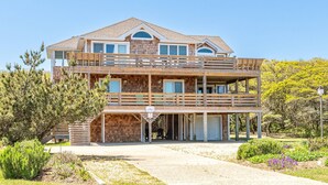 Ein zweistöckiges Holzhaus mit Balkon, überdachter Veranda und Auffahrt.