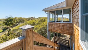 Eine Holzterrasse mit Glasgeländer, die auf eine üppige Landschaft blickt.