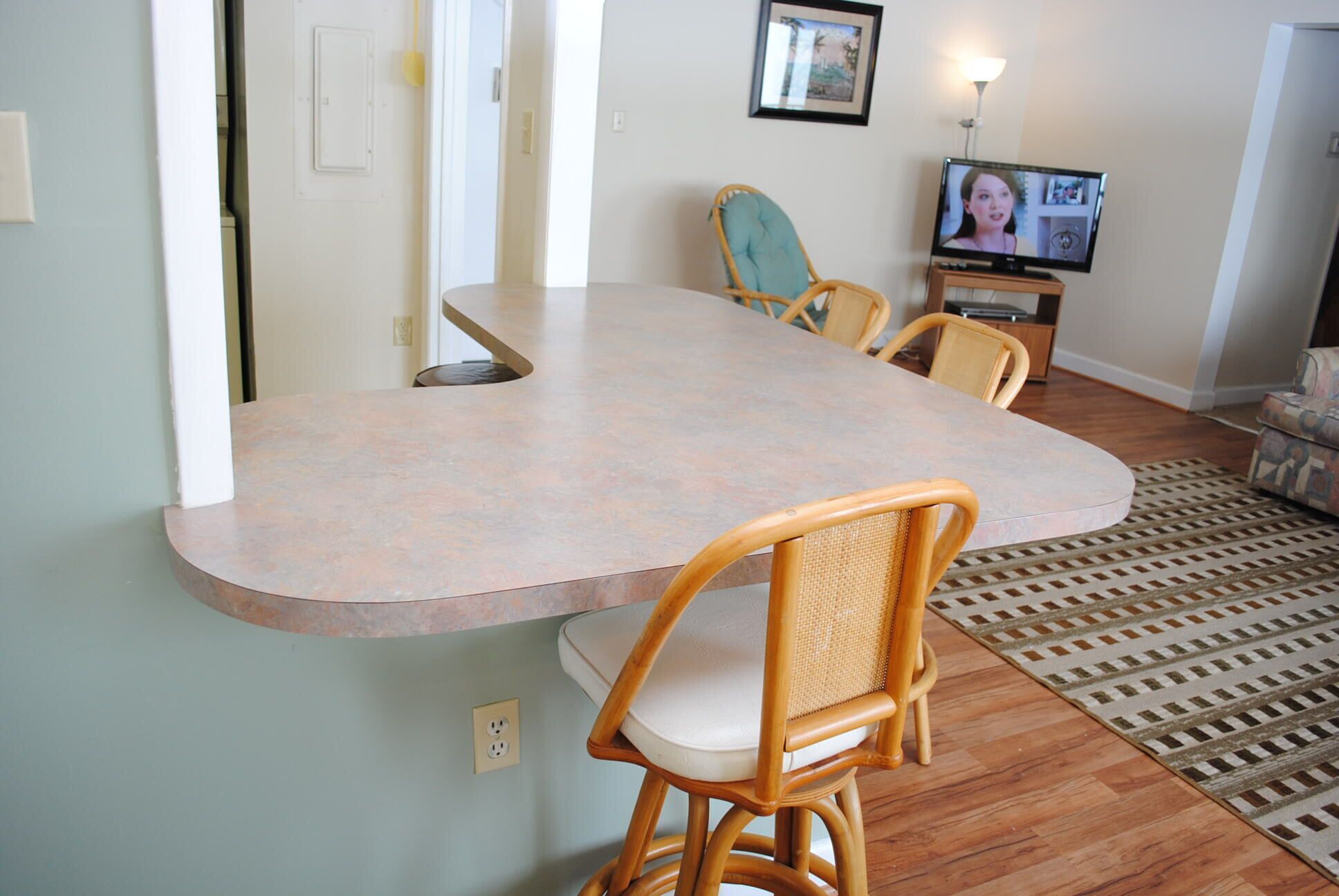 A dining area with a long table and two wicker chairs.