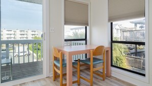 Ein Balkon mit Tisch und Stühlen, Blick auf die Straße und ein Gebäude im Hintergrund.