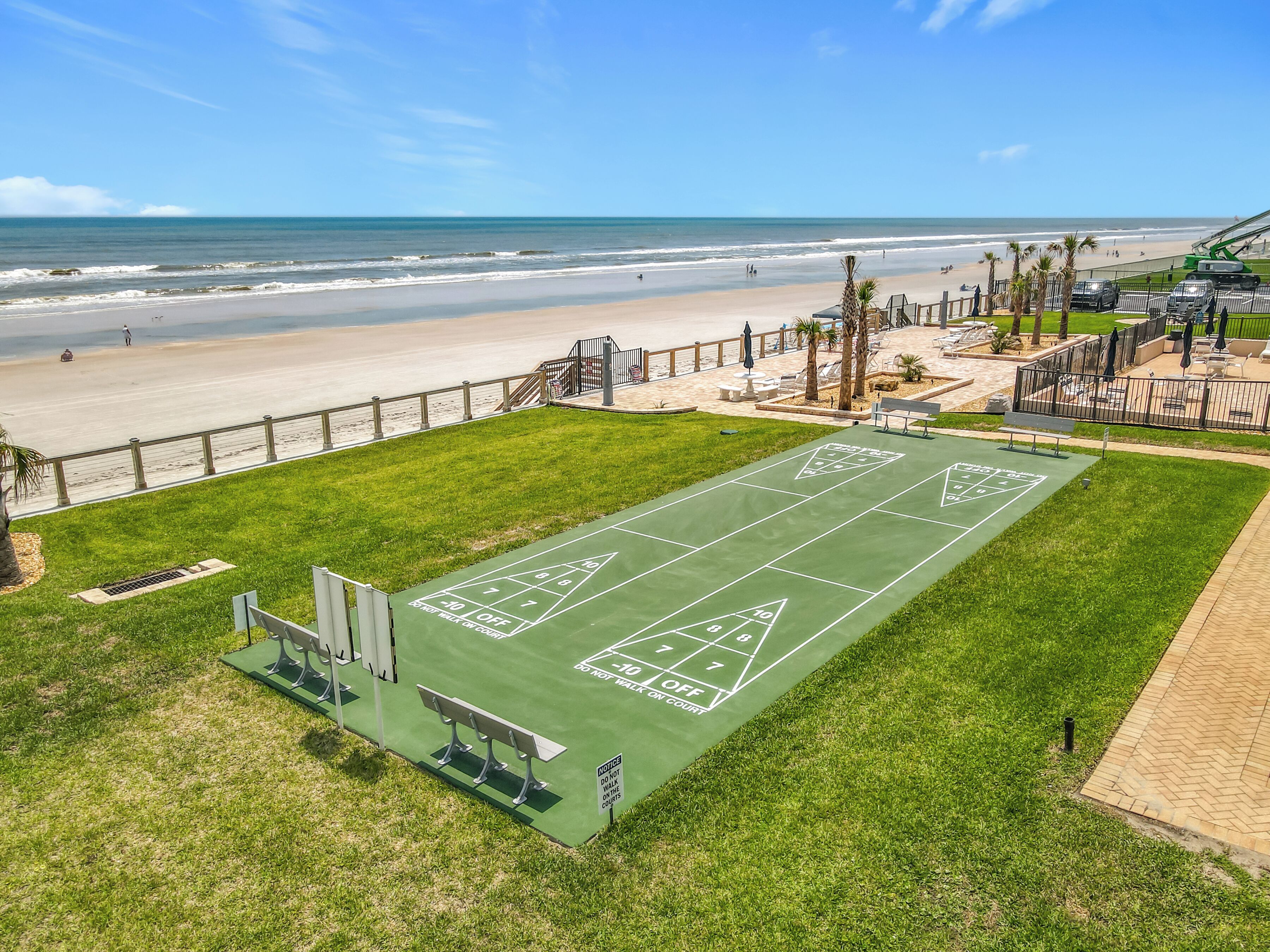 Un terrain de jeu de shuffleboard vert, offrant une vue sur la plage et l’océan.