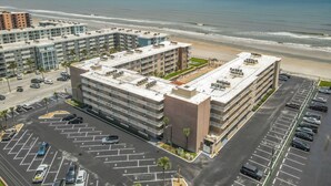 A multi-story parking structure adjacent to a beachfront hotel with a view of the ocean. - Cute 2/2!Direct Oceanfront Complex on the No Drive Beach in NSB! (New Smyrna Beach)