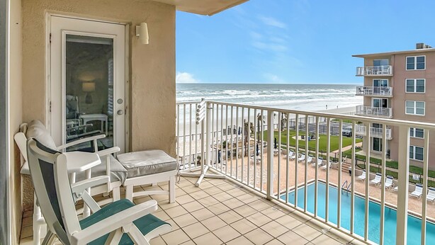 A balcony with a view of the ocean, a pool, and a building with multiple floors. - Cute 2/2!Direct Oceanfront Complex on the No Drive Beach in NSB! (New Smyrna Beach)