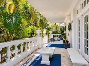 A covered outdoor area with a white balustrade, a white table, and benches. - South of Fifth 1BR Condo - Heated Pool, Balcony & Walk to Beach (Miami Beach)