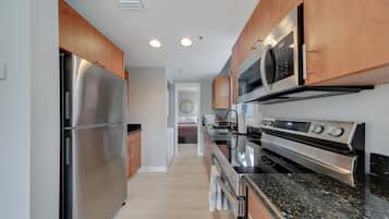 Una cocina moderna con electrodomésticos de acero inoxidable, armarios de madera y encimera de granito.