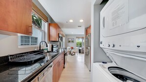 A modern kitchen with wooden cabinets, a black countertop, and a built-in dishwasher.