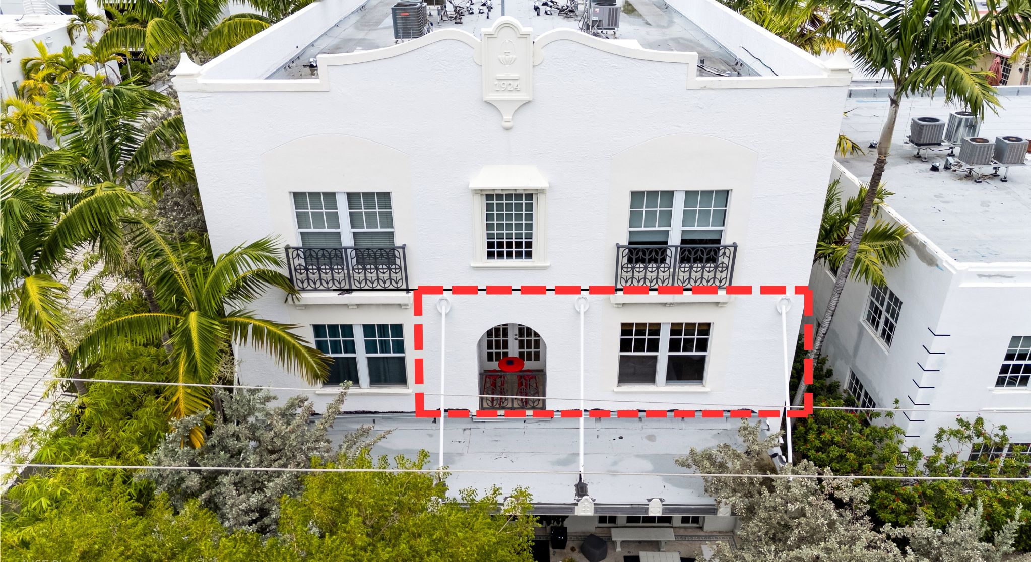 Un edificio blanco con entrada central, varias ventanas y balcones.