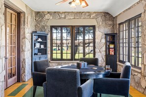 A stone-walled room with a round table, four chairs, and a bookshelf. - 10 Bedroom Hill Country Retreat with Pickleball, Tennis and Pool- Stonehaven Ran (San Marcos)