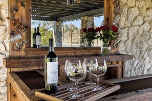 A wooden wine rack with a bottle of wine and three glasses.