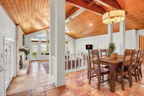 Un comedor amplio con mesa y sillas de madera, una araña y vistas al exterior.
