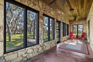 A covered outdoor area with stone walls, large windows, and a view of a grassy landscape.