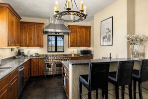 A kitchen with wooden cabinets, a stainless steel range, a built-in oven, a microwave, and a large island with bar stools.