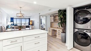 A modern kitchen with white cabinetry, a central island, and a built-in washer-dryer unit.