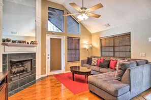 Cozy living space with a fireplace, sectional sofa, and large windows.