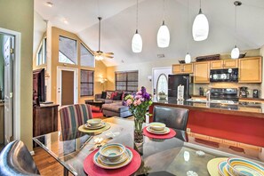 Enjoy meals in a stylish dining area with a glass table, comfortable sofa, and modern kitchen.