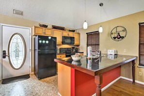 Compact kitchen with modern appliances, central island, and wooden cabinets.
