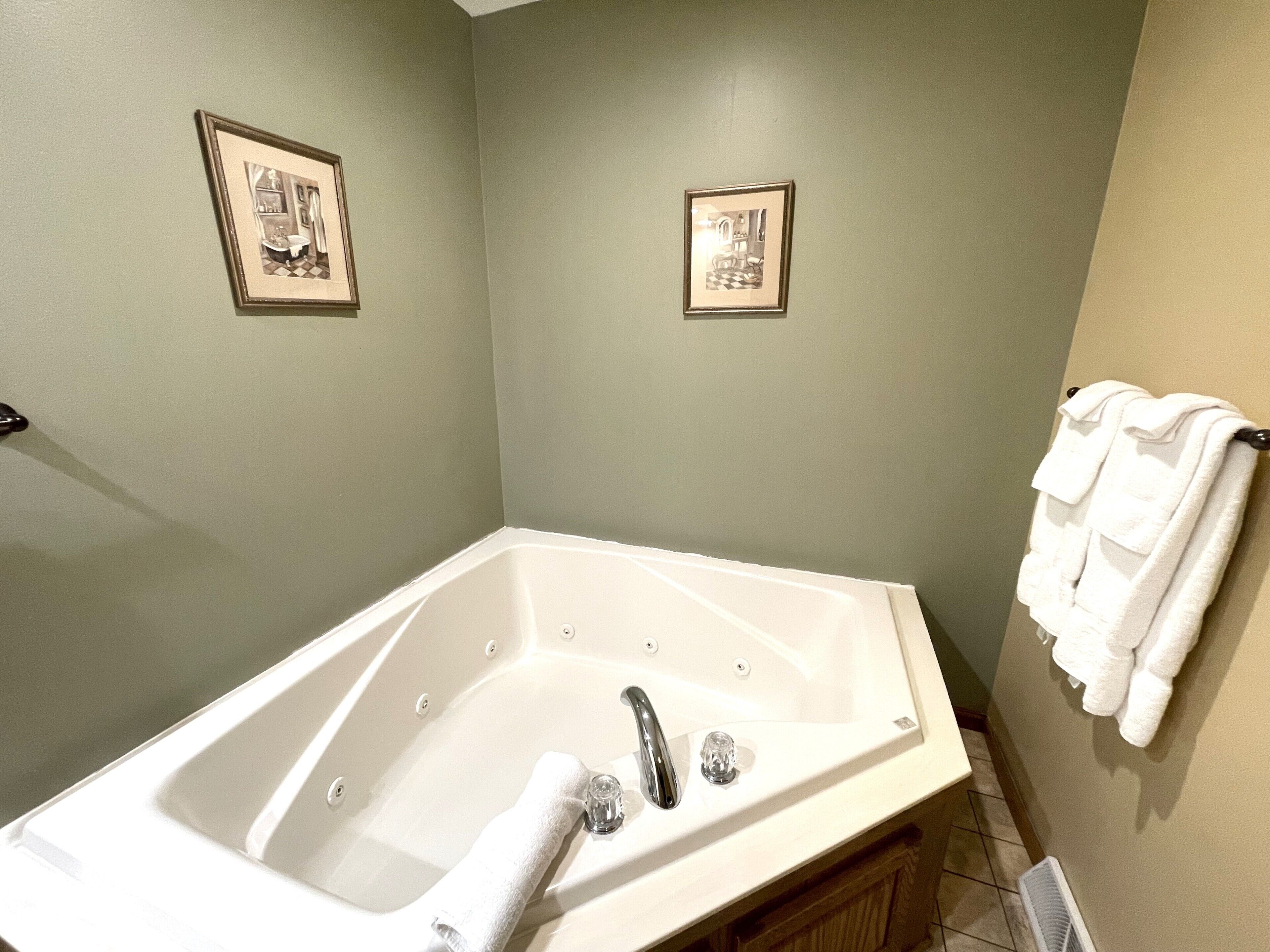 Ein Badezimmer mit einer weißen Badewanne, zwei gerahmten Bildern an der Wand und einem Handtuchhalter mit Handtüchern.