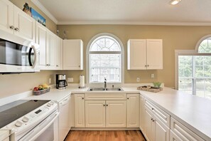 A modern kitchen with white cabinetry, a built-in microwave, an oven, and a sink.