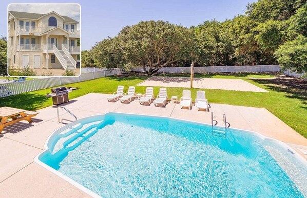 A swimming pool with lounge chairs, a barbecue area, and a large building in the background.