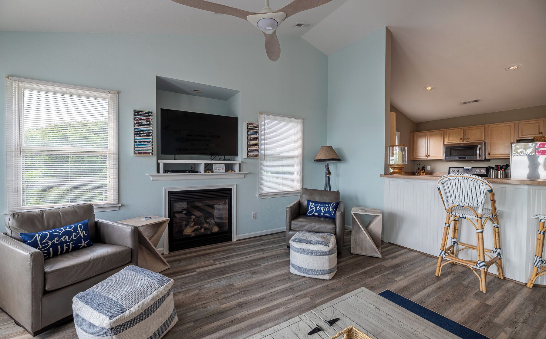 A living room with a fireplace, a television, and a kitchen area with wooden cabinets and a microwave.