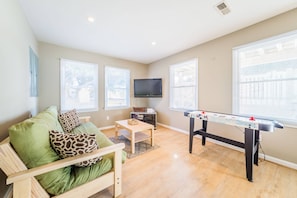 Relax in this spacious room with a high ceiling, large windows, and a comfortable sofa, perfect for unwinding and enjoying entertainment options.