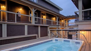 A swimming pool with a wooden deck and a building with multiple balconies. - Ski-In/Ski-Out! Hot tub access, sleeps 9, Heated garage parking! (Breckenridge)
