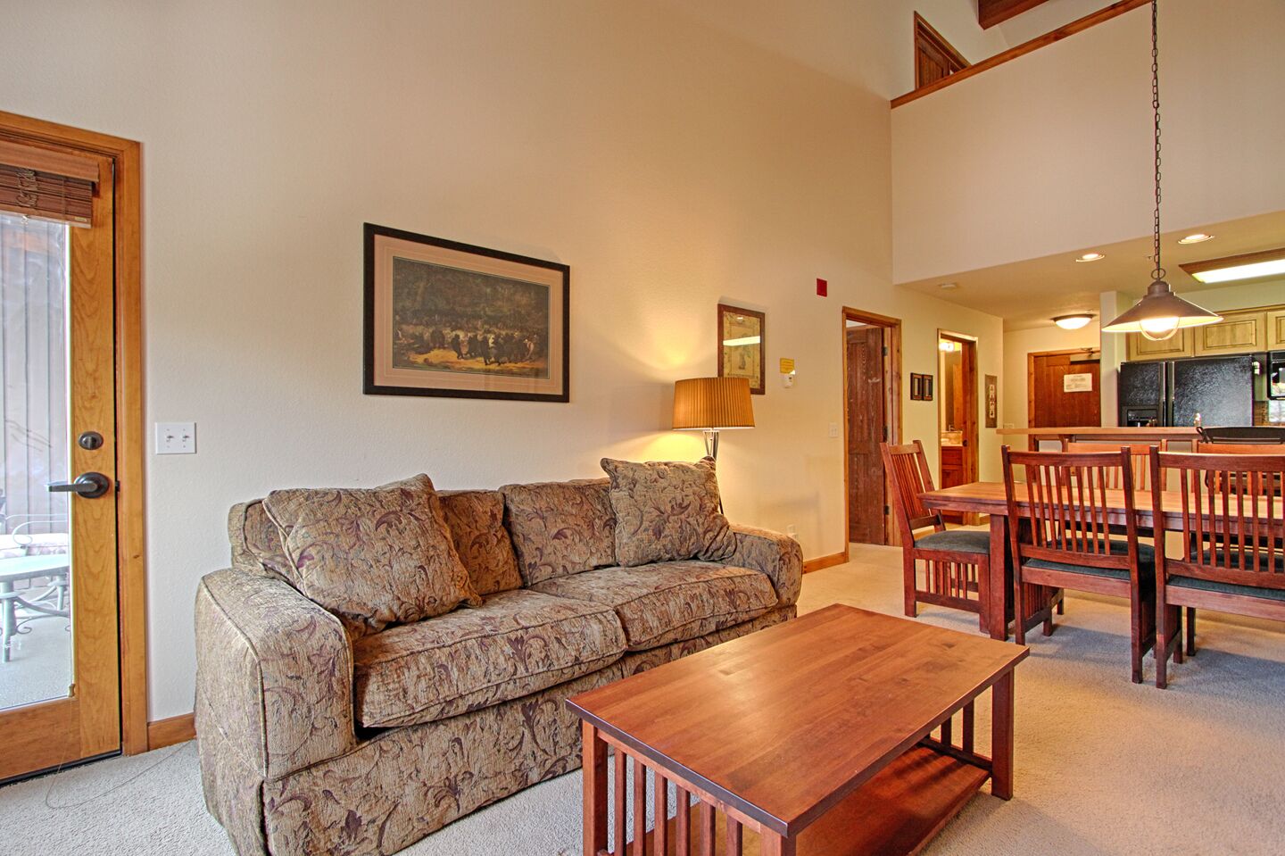 A living room with a sofa, a wooden coffee table, and a dining area with a table and chairs.