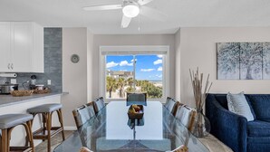 A modern kitchen with white cabinets, a dining area with a glass table, and a view of the ocean. - Completely Renovated Oceanfront Unit in Quaint Surfside Beach! SC205b (Surfside Beach)