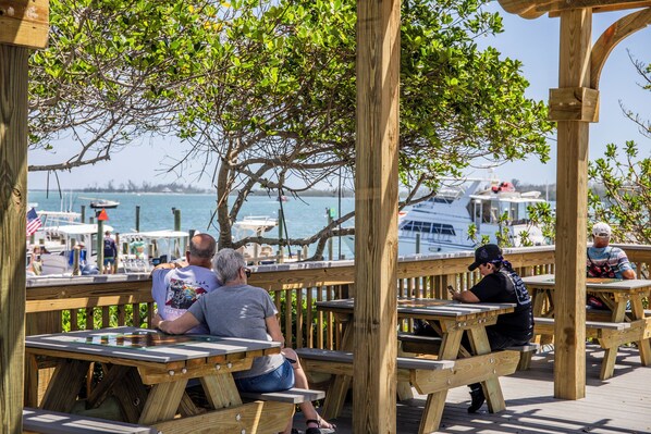 A wooden deck with picnic tables, overlooking a marina with boats.