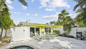 Un jardin avec une piscine, un espace salon extérieur et un barbecue.
