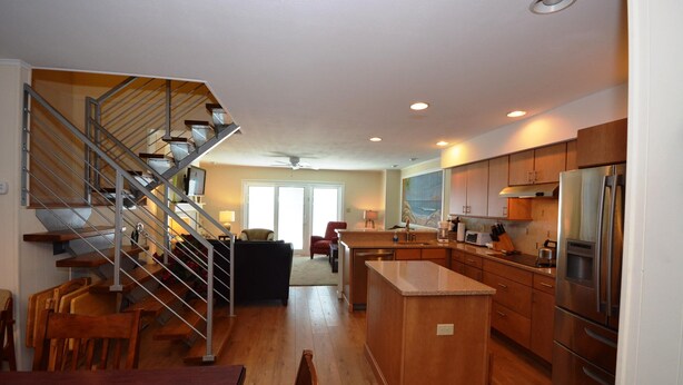 A modern kitchen with wooden cabinets, a stainless steel refrigerator, and a central island. - Unique, stylish 4 bedroom bayside townhouse with free WiFi, pier boat docking, and a breathtaking view of the ocean located midtown on the bay water and just a few blocks from the beach! (Ocean City)