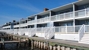 A row of waterfront buildings with multiple balconies and a wooden dock extending into the water. - Unique, stylish 4 bedroom bayside townhouse with free WiFi, pier boat docking, and a breathtaking view of the ocean located midtown on the bay water and just a few blocks from the beach! (Ocean City)