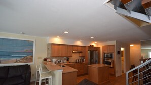 A modern kitchen with wooden cabinets, a central island, and stainless steel appliances. - Unique, stylish 4 bedroom bayside townhouse with free WiFi, pier boat docking, and a breathtaking view of the ocean located midtown on the bay water and just a few blocks from the beach! (Ocean City)