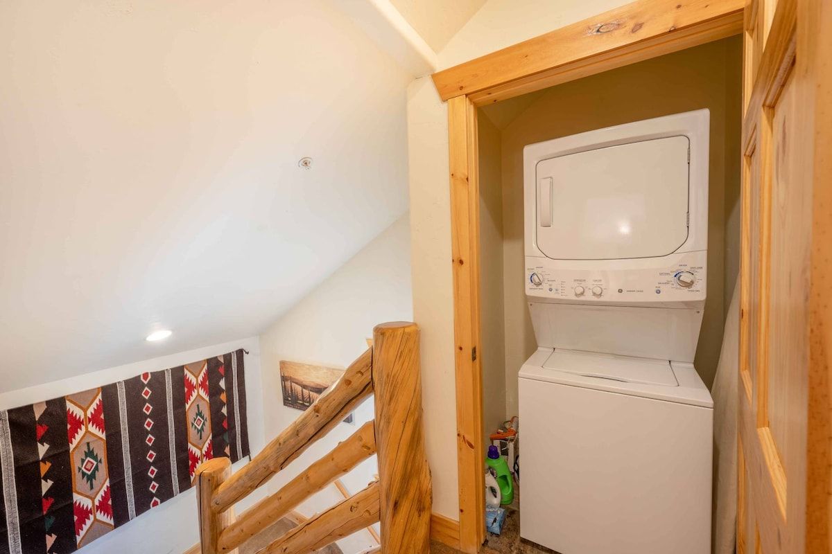 A laundry room with a washing machine and a wooden staircase.