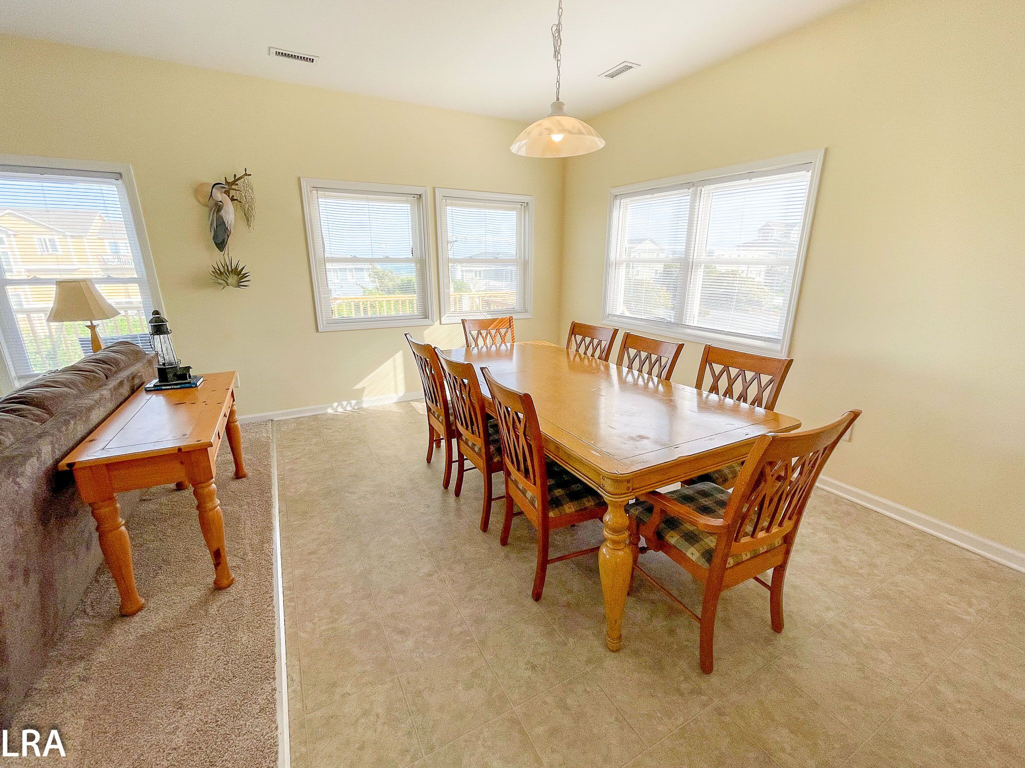 A dining room with a wooden table and chairs, a sofa, and a lamp.
