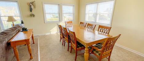 A dining room with a wooden table and chairs, a sofa, and a lamp.