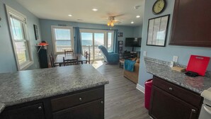 A kitchen with dark wooden cabinets, a granite countertop, and a red cutting board. - Island Delights II – Sun, Sand & Simple Fun (Surf City)