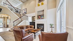 A spacious living room with a fireplace, leather furniture, and a staircase. - Homestead Holly: Game Loft, Private Pool, Water Park, Near Disney (Kissimmee)
