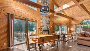 A spacious wooden interior with a large dining table, stone pillar, and a fireplace.