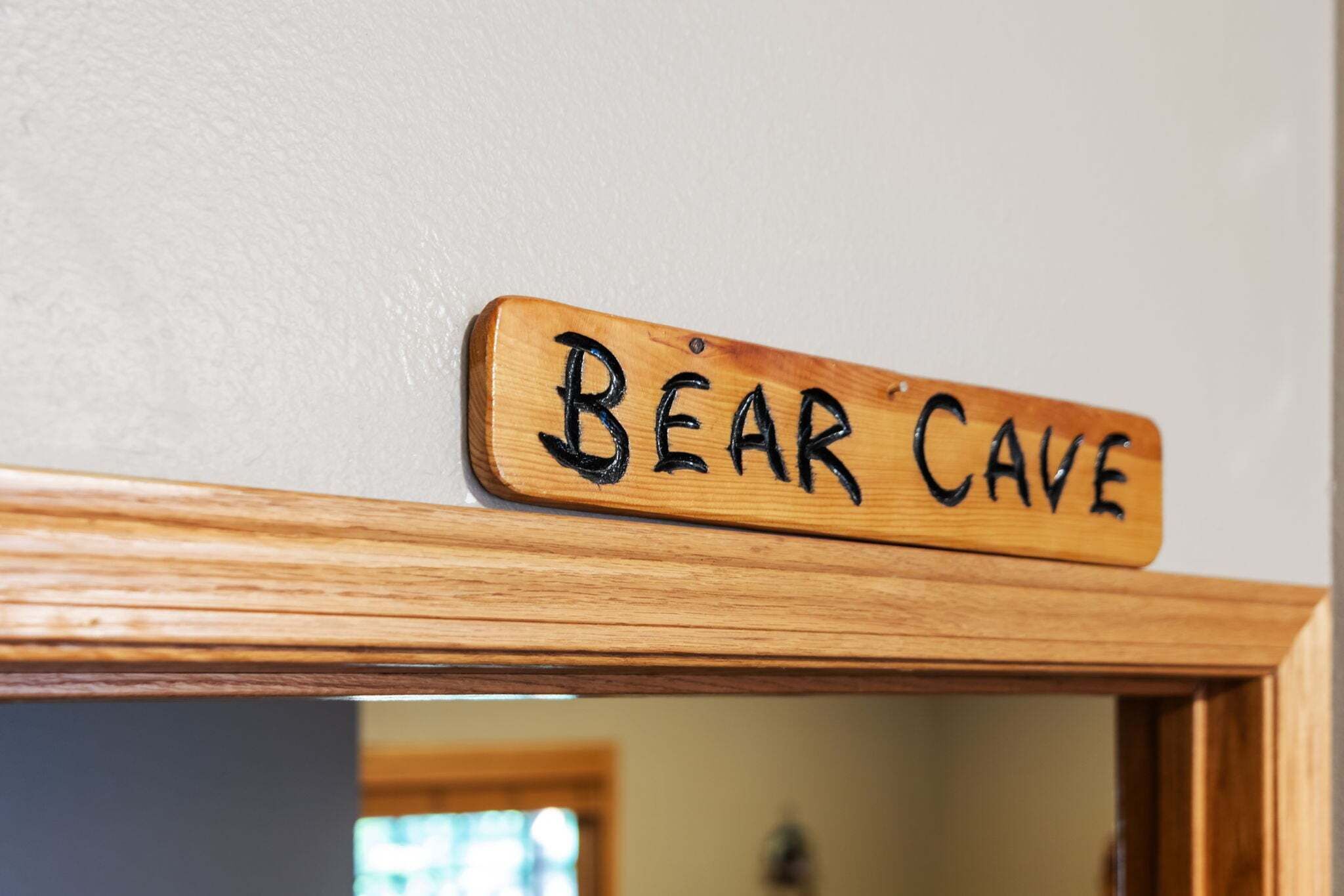 Un letrero de madera con el texto 'Bear Cave' fijado a una pared.