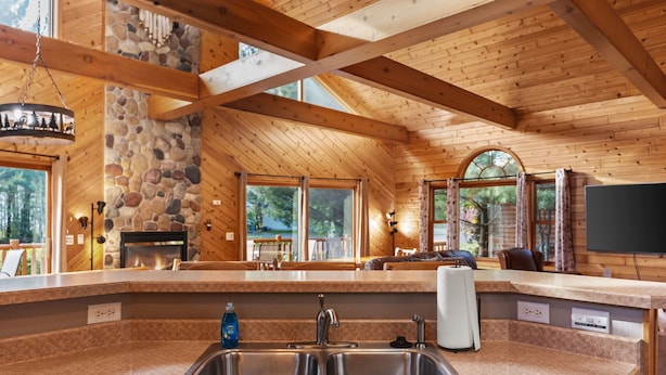 A kitchen with a stone fireplace, large windows, and a stone wall.