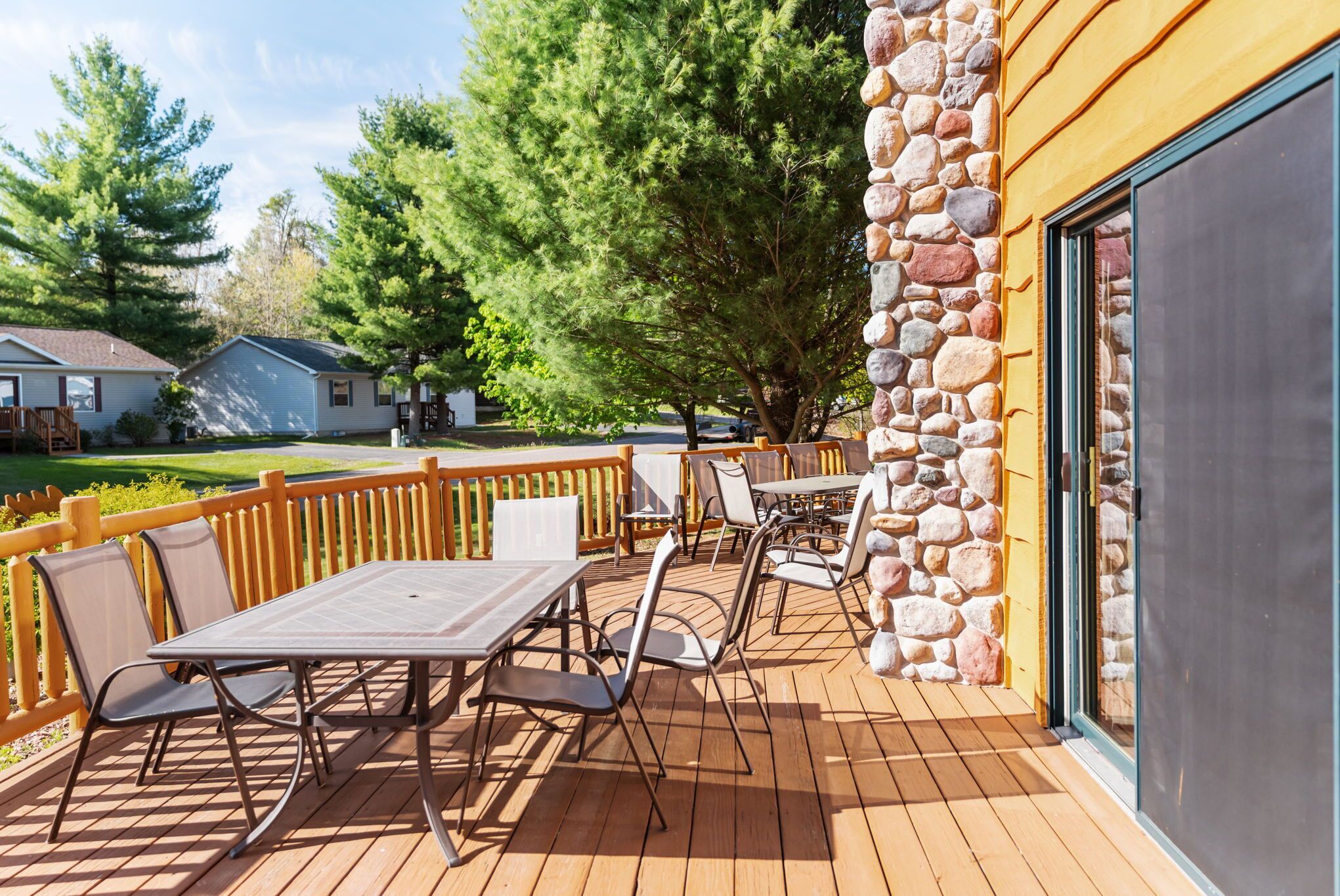 A deck with outdoor furniture, a stone wall, and a view of the surrounding area.