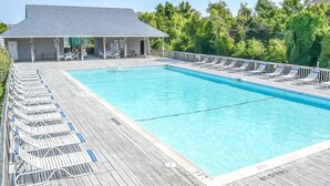 Ein rechteckiger Pool mit Holzterrasse und Liegestühlen.