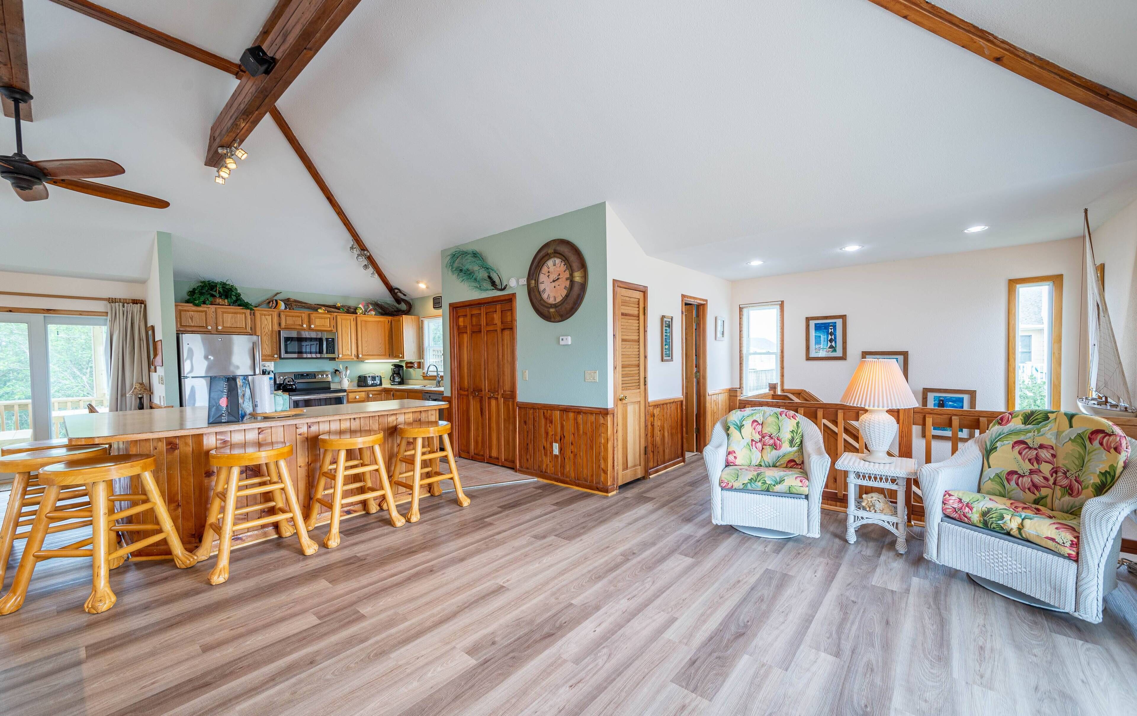 A spacious kitchen with wooden cabinets, a central island with stools, and a dining area with wicker furniture.