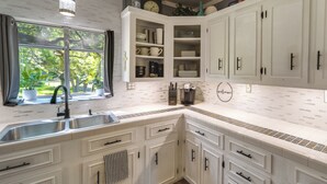 A kitchen with white cabinets, a double sink, and a window with a view of trees. - Waterfront Lake LBJ Cabin w/ Private Dock! (Burnet)